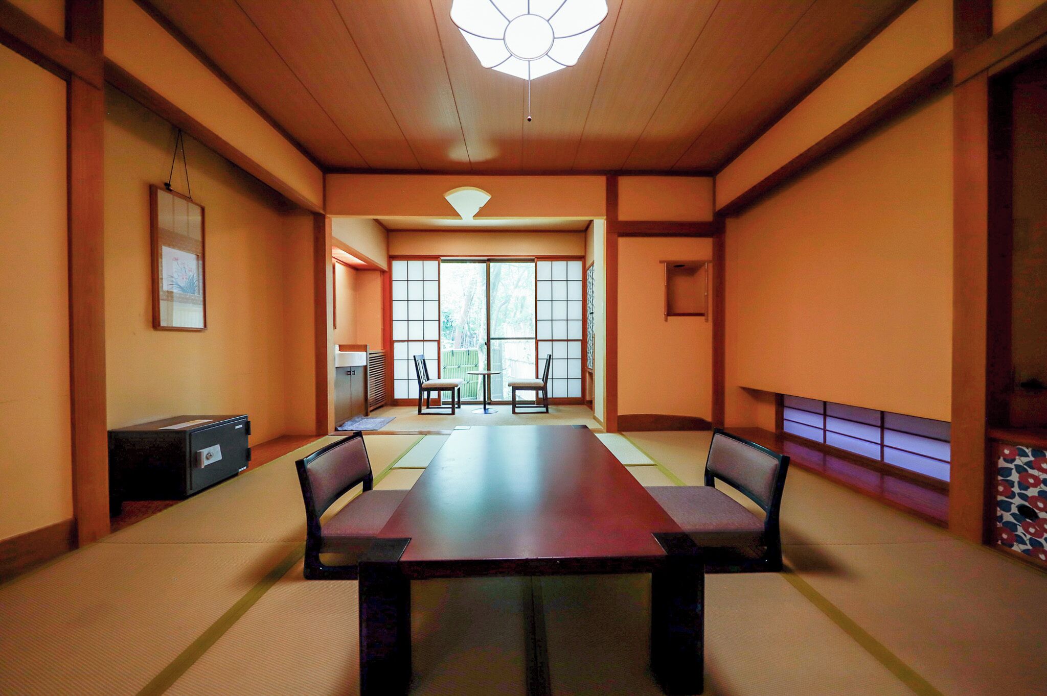 A traditional Japanese room with tatami flooring, a low table with cushions, sliding doors, and a ceiling fan.