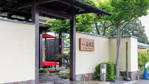 A traditional Japanese building with a stone pathway leading to a covered entrance. A red umbrella is visible under the entrance, and a signboard with Japanese characters is mounted on the wall. - Ryokan Kiritani Hakoneso (Hakone)