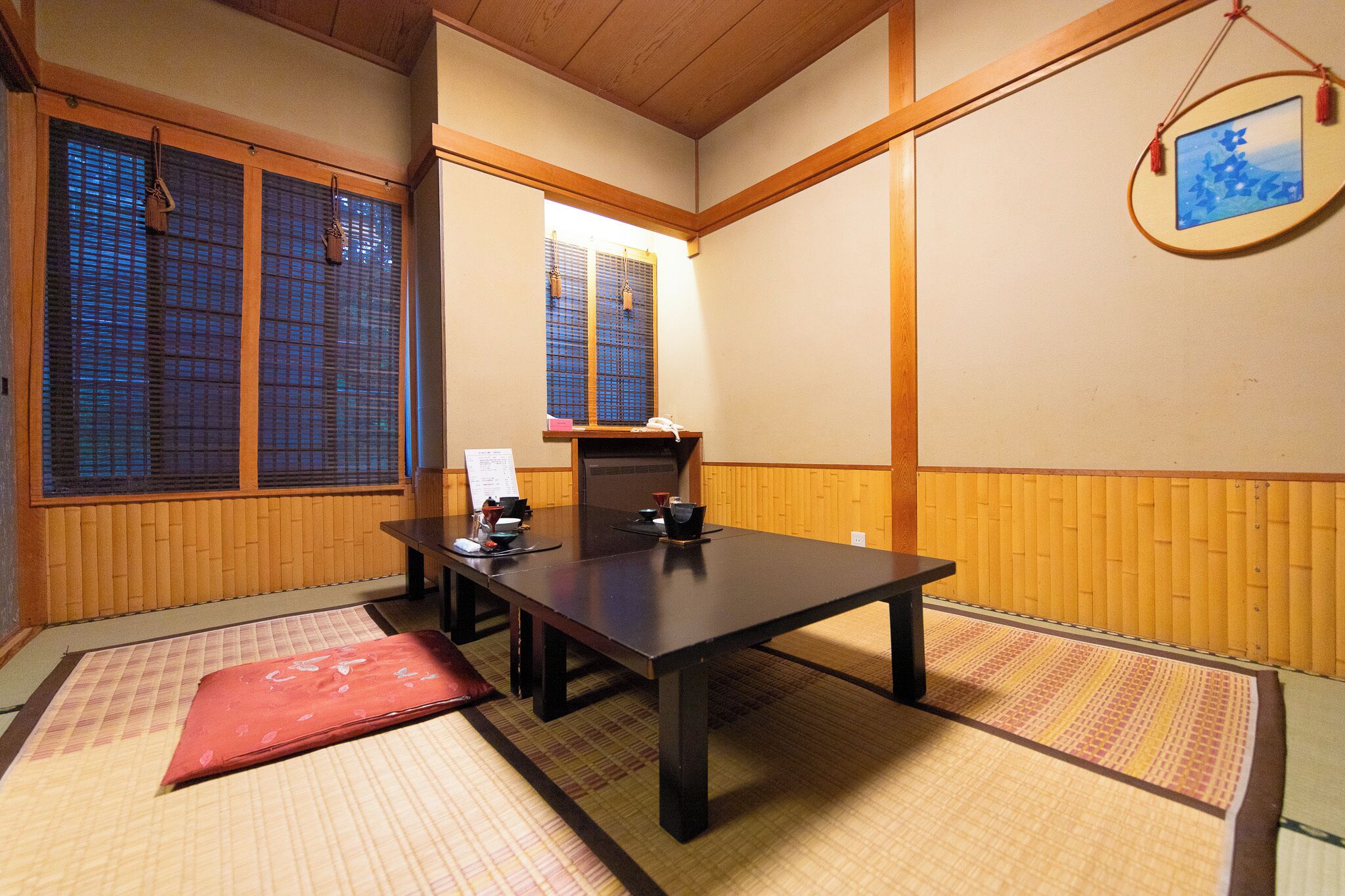A traditional Japanese room with tatami flooring, a low table with a tea set, and sliding doors.