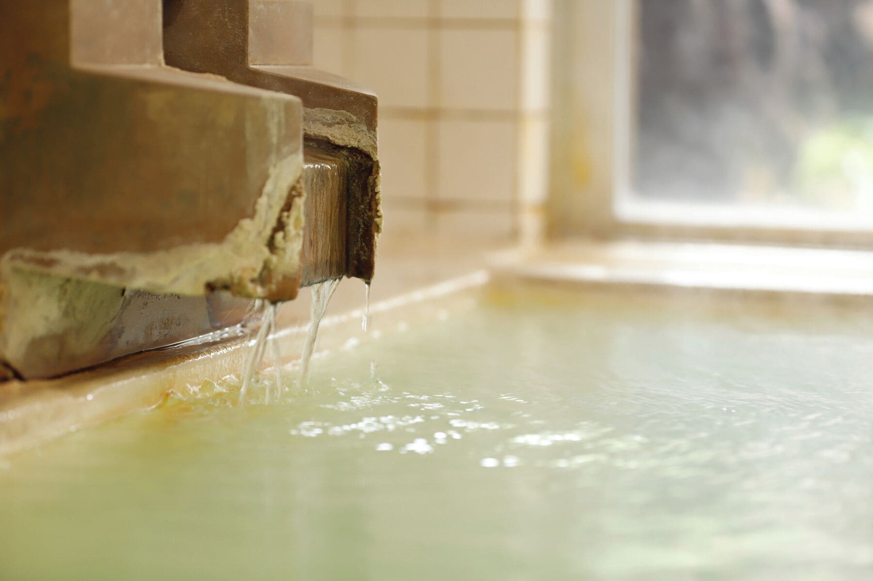 A close-up of a faucet with water running into a sink.