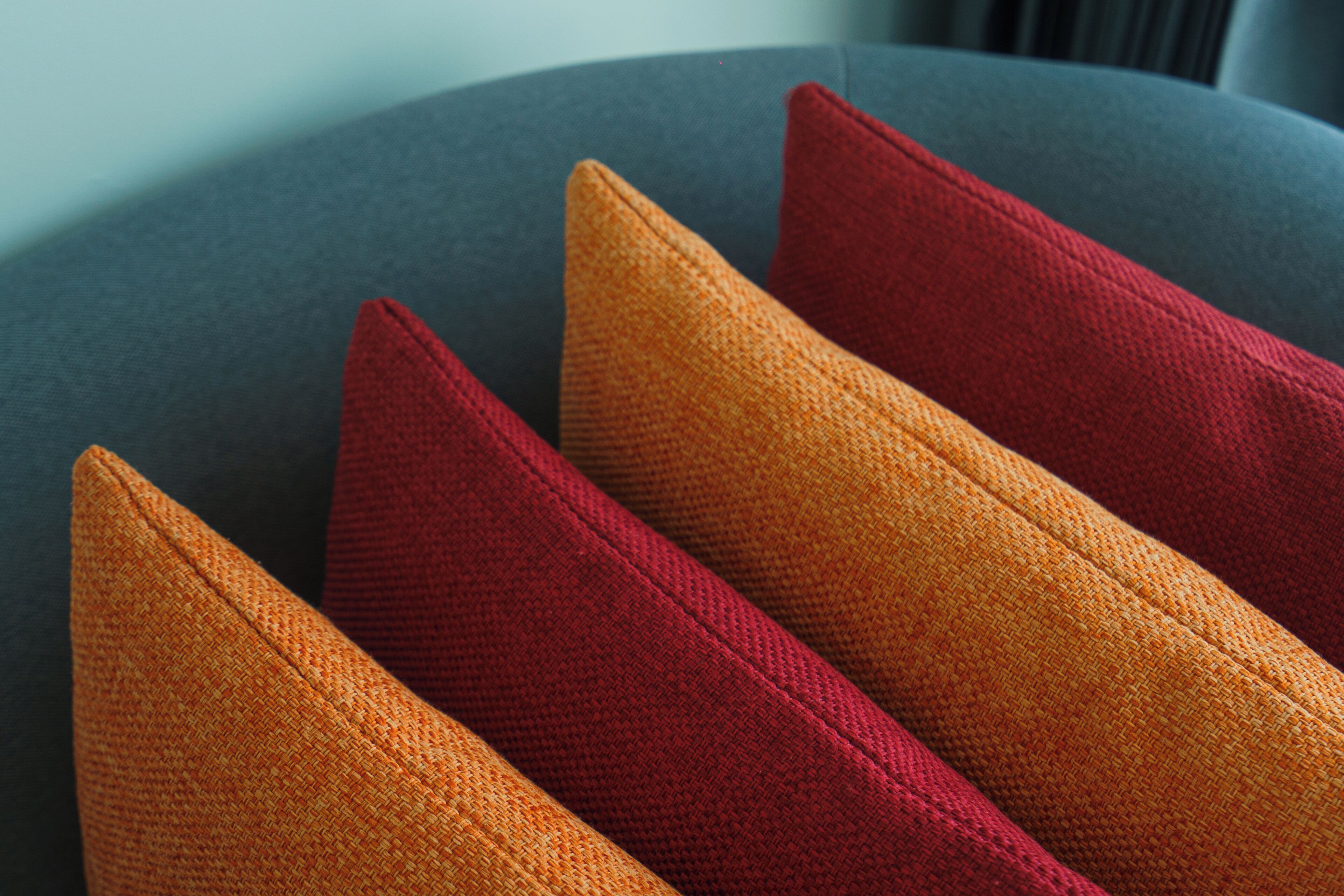 A close-up of four cushions with a woven texture, arranged in a staggered pattern.