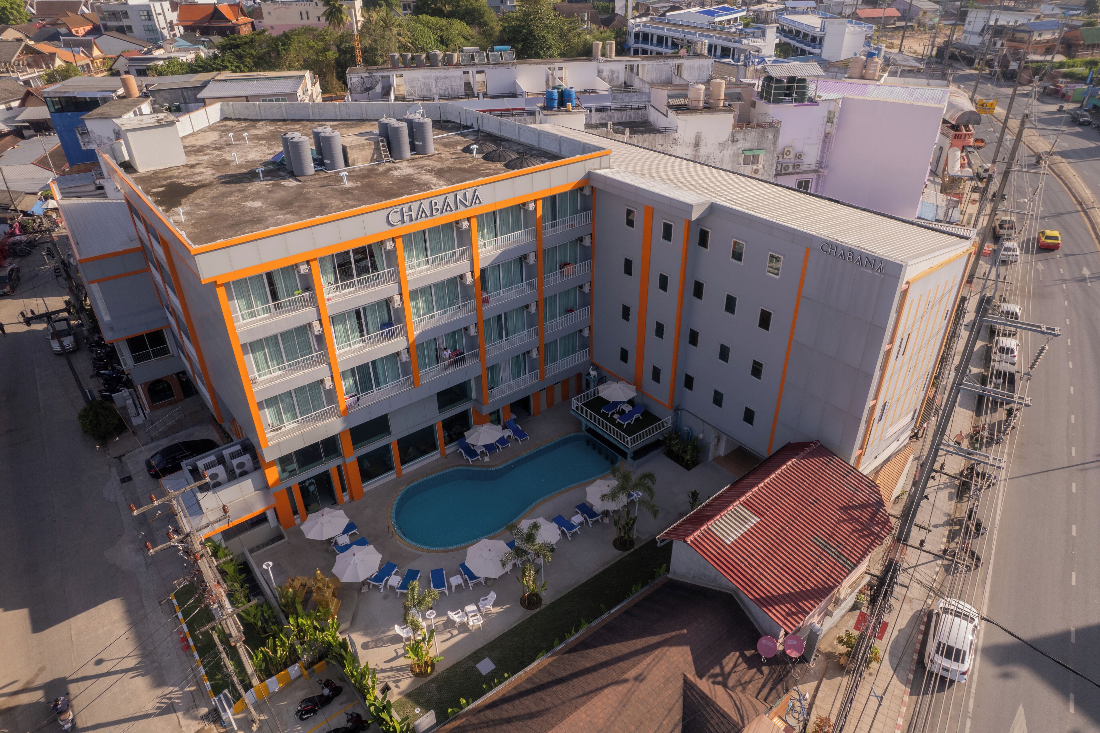 A multi-story hotel with a rooftop pool, balconies, and outdoor seating areas.