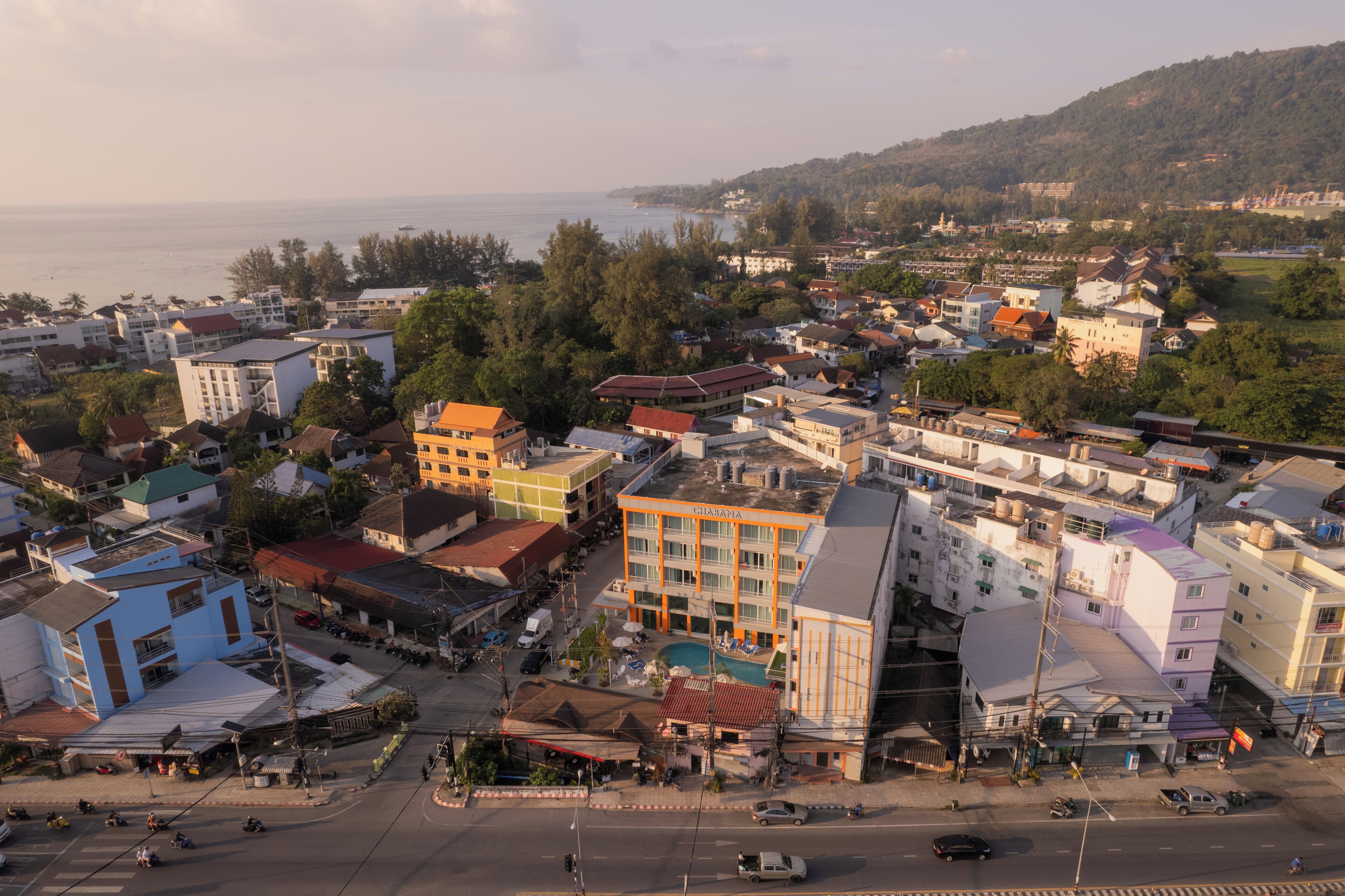 Une ville côtière où se côtoient des bâtiments résidentiels et commerciaux, dont un hôtel de renom doté d’une piscine.