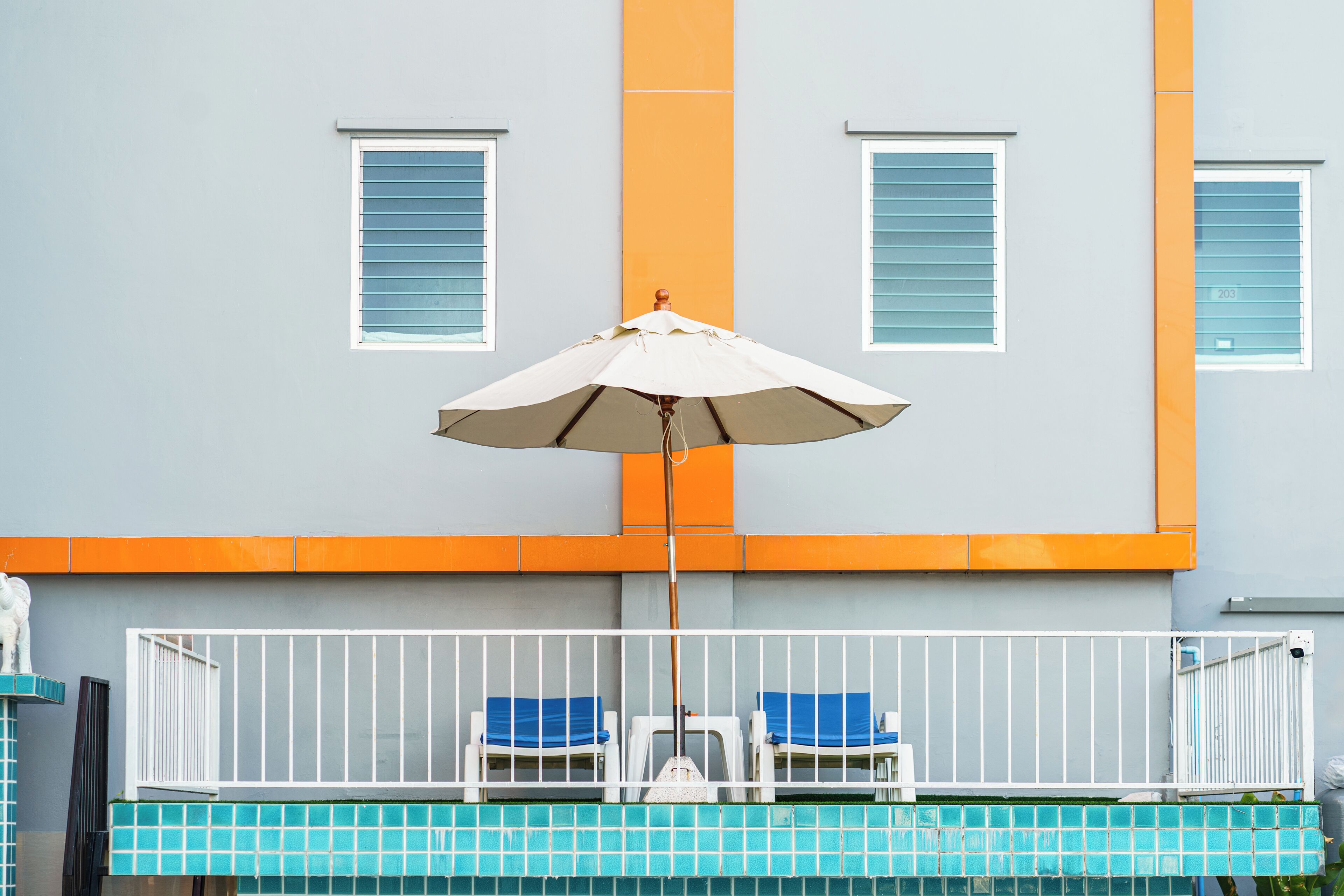 Un área de piscina con dos sillones de jardín y una sombrilla.