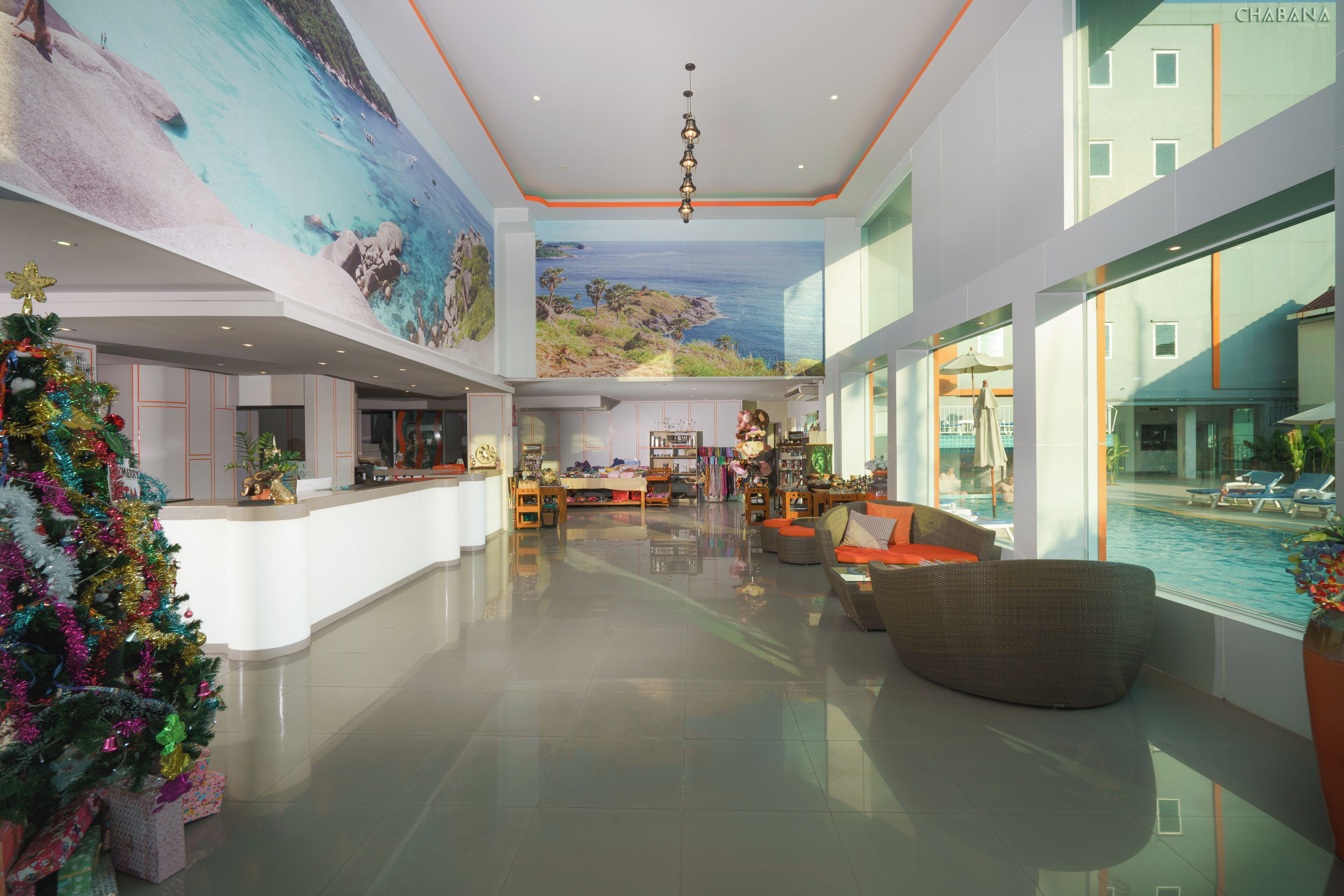 A spacious lobby with a large mural, a reception desk, seating area, and a view of the pool.