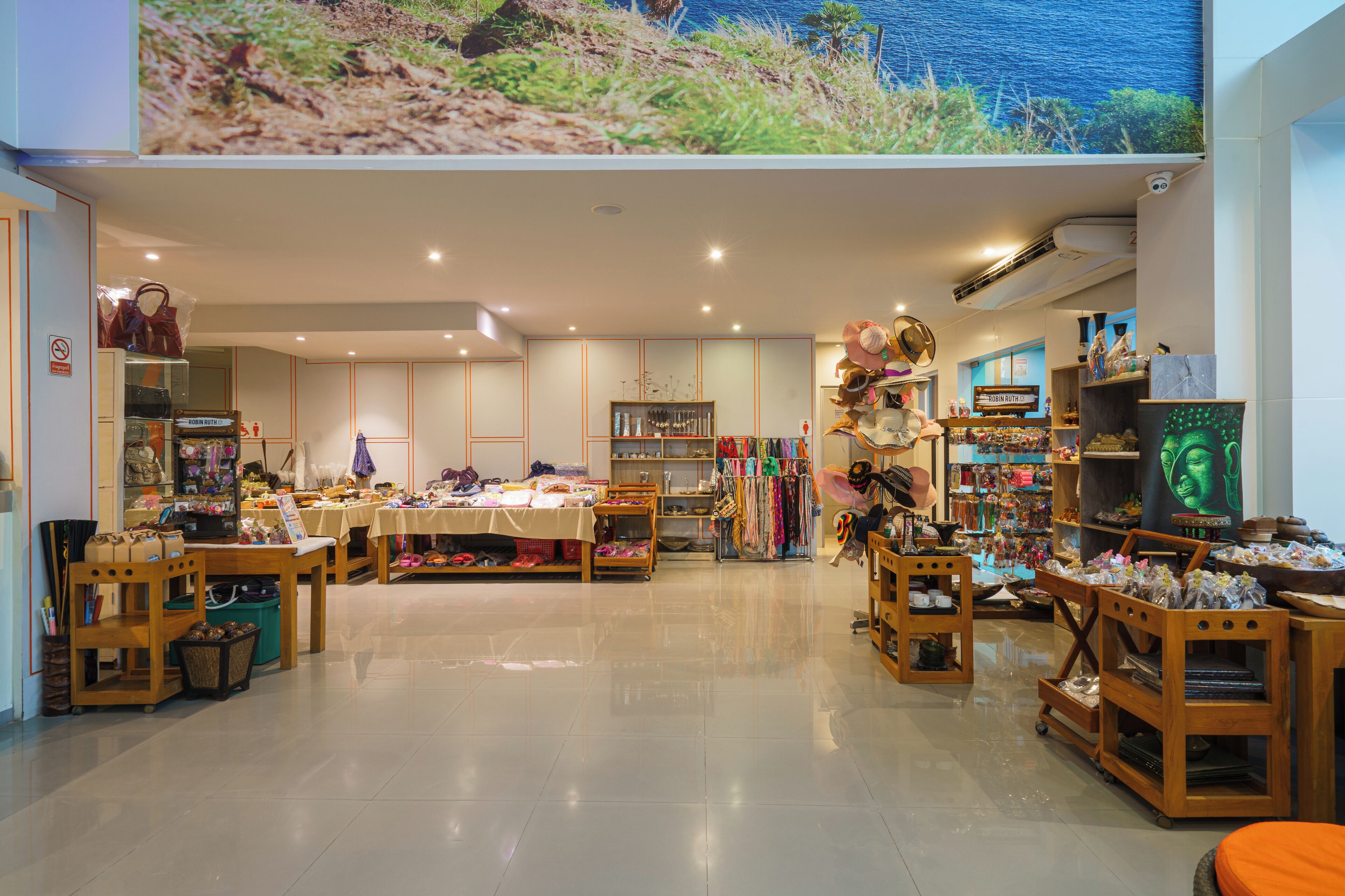 Una boutique espaciosa con mobiliario de madera, diversa ropa y accesorios a la vista, y una gran estatua de Buda.