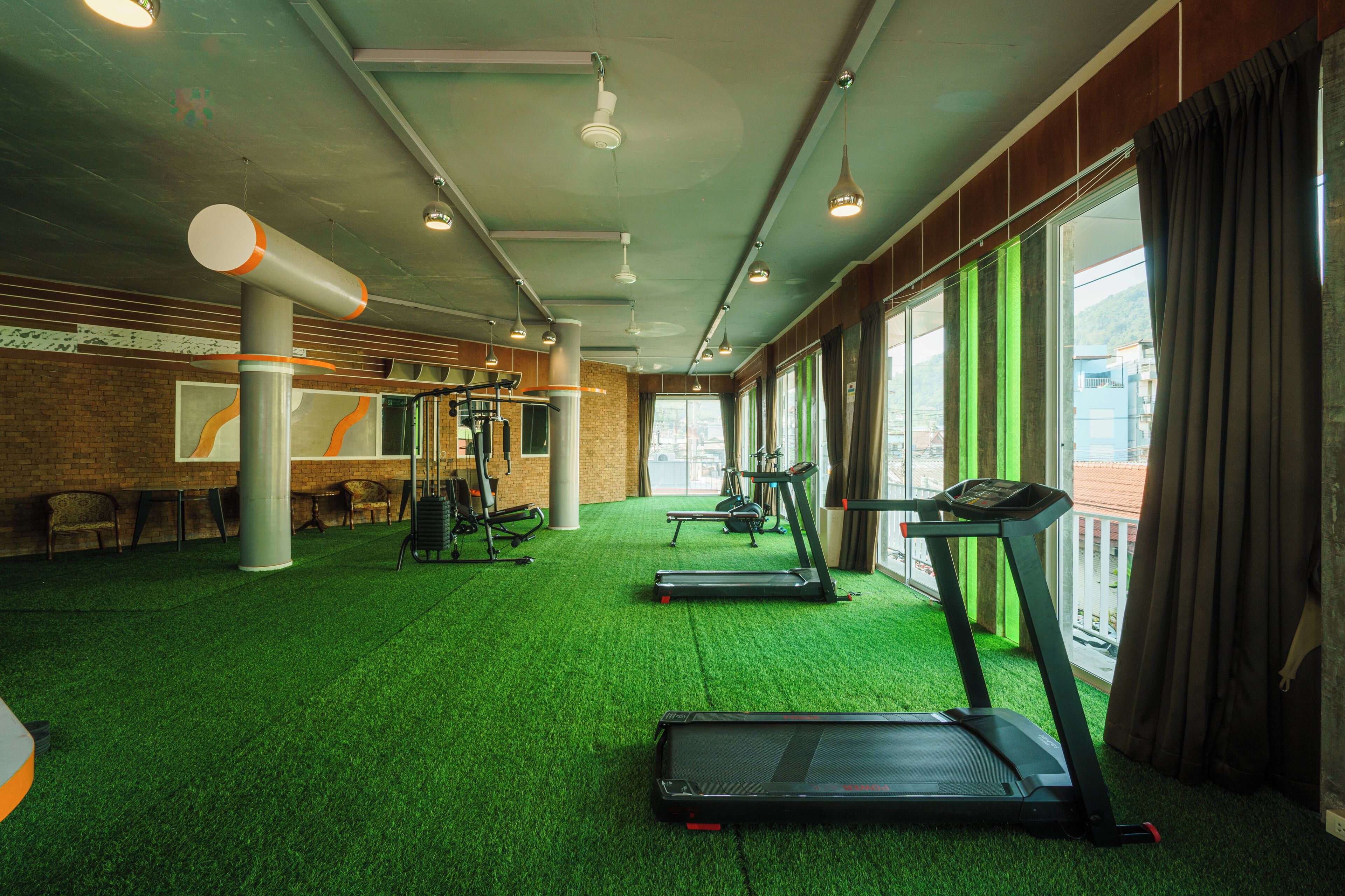 A gym with treadmills, exercise equipment, and a green artificial turf floor.
