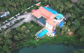 Vista aérea de un complejo turístico con varias edificaciones, una piscina y una extensión de agua.