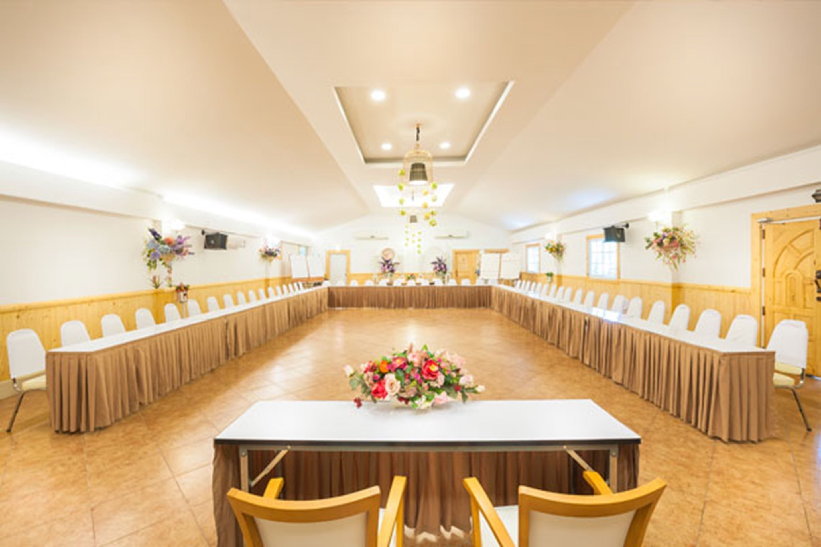 Un salón de conferencias con una larga mesa, sillas y centros de mesa con flores.