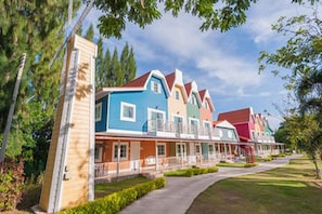 Eine Reihe bunter Häuser mit unterschiedlicher Architektur, ein gepflasterter Weg und ein gepflegter Rasen.