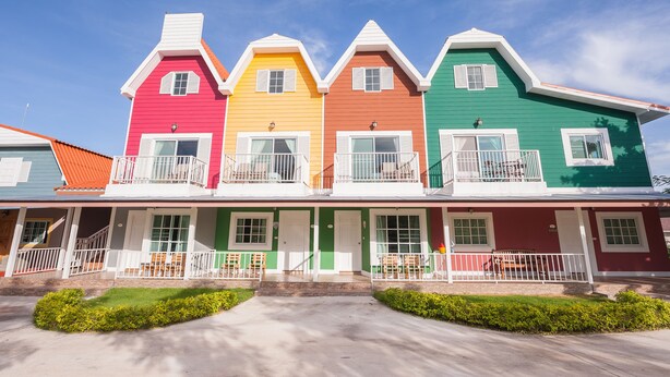 A row of colorful houses with balconies and front porches. - Belmont Village (Pak Chong)