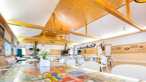 A spacious room with a high wooden ceiling, a large table covered with a map, and a sign reading "Belmont Village". - Belmont Village (Pak Chong)