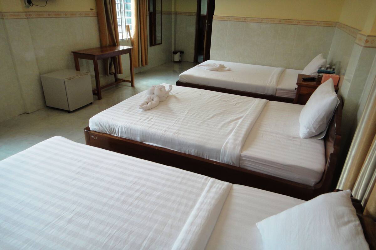 A hotel room with two beds, a small table, and a chair.