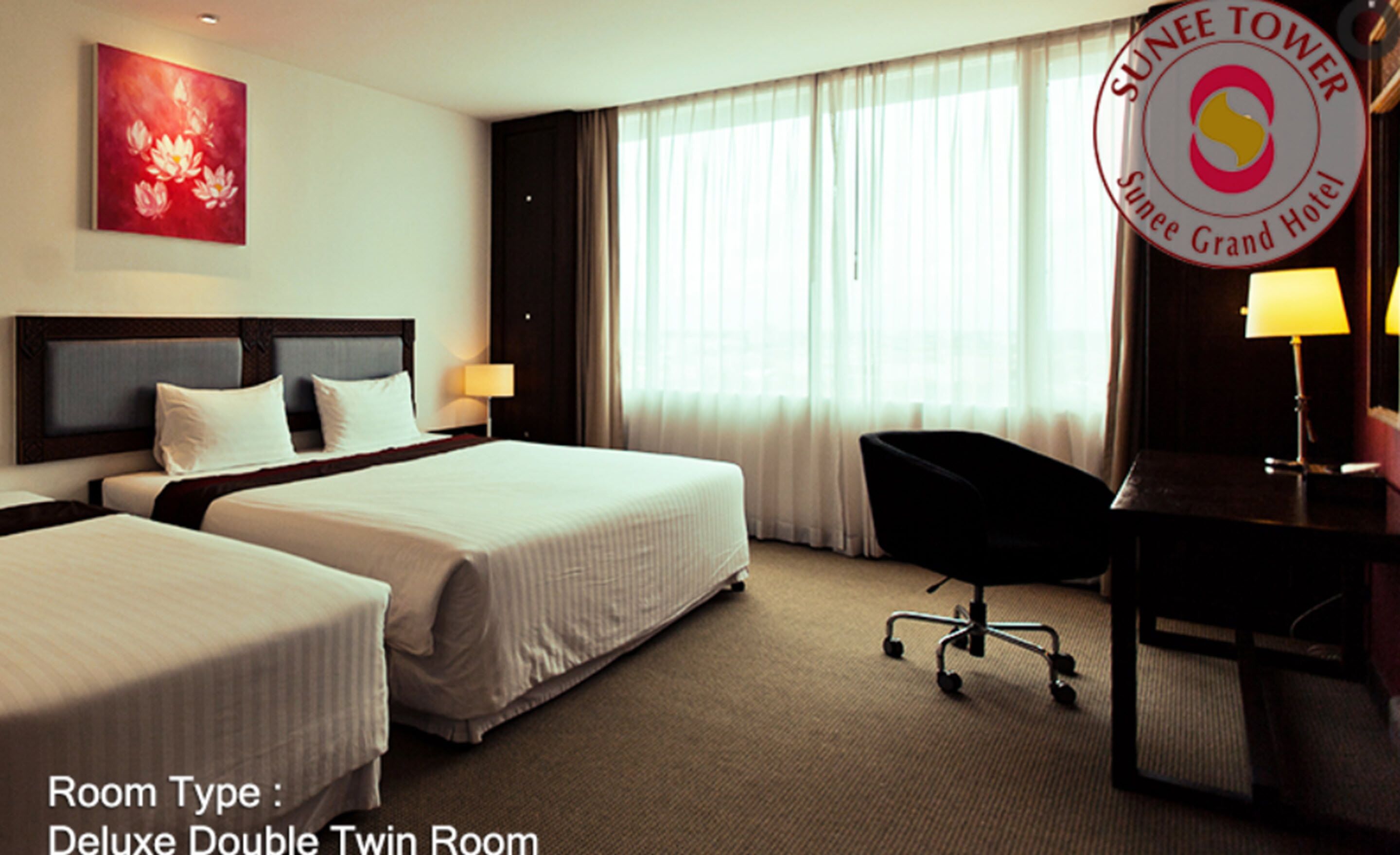 A Deluxe Double Twin Room with two beds, a desk, a chair, and a large window with curtains.