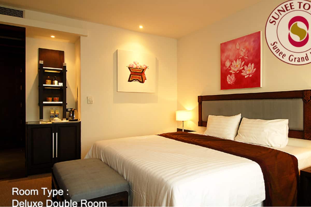 Una habitación doble de lujo con cama, mesita de noche, lámpara y una obra de arte colgada en la pared.