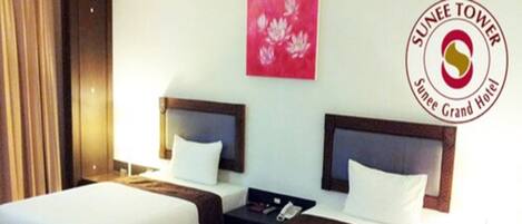 A Deluxe Twin Room with two beds, bedside tables, and a nightstand.