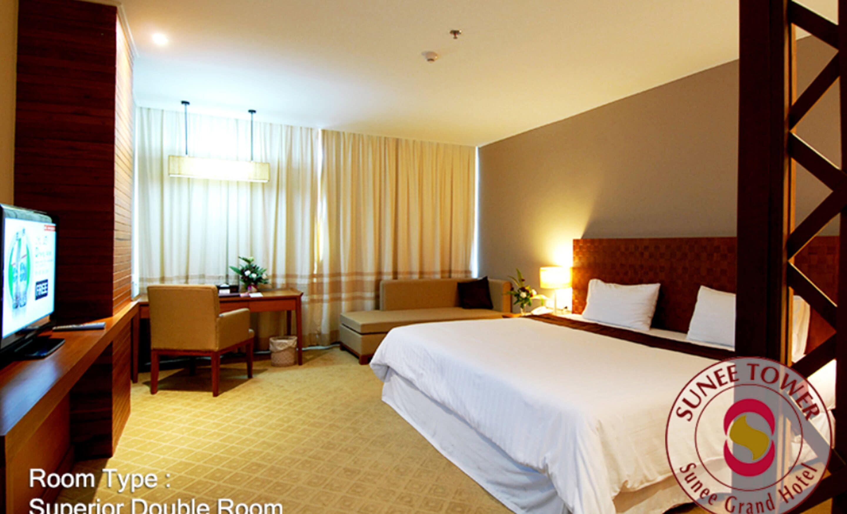 A Superior Double Room with a bed, desk, chair, and a television.