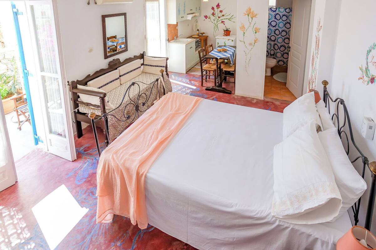 Un dormitorio con cama, una silla, una mesa y vistas al baño.