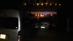Un parking peu éclairé où deux véhicules sont stationnés sous une structure.