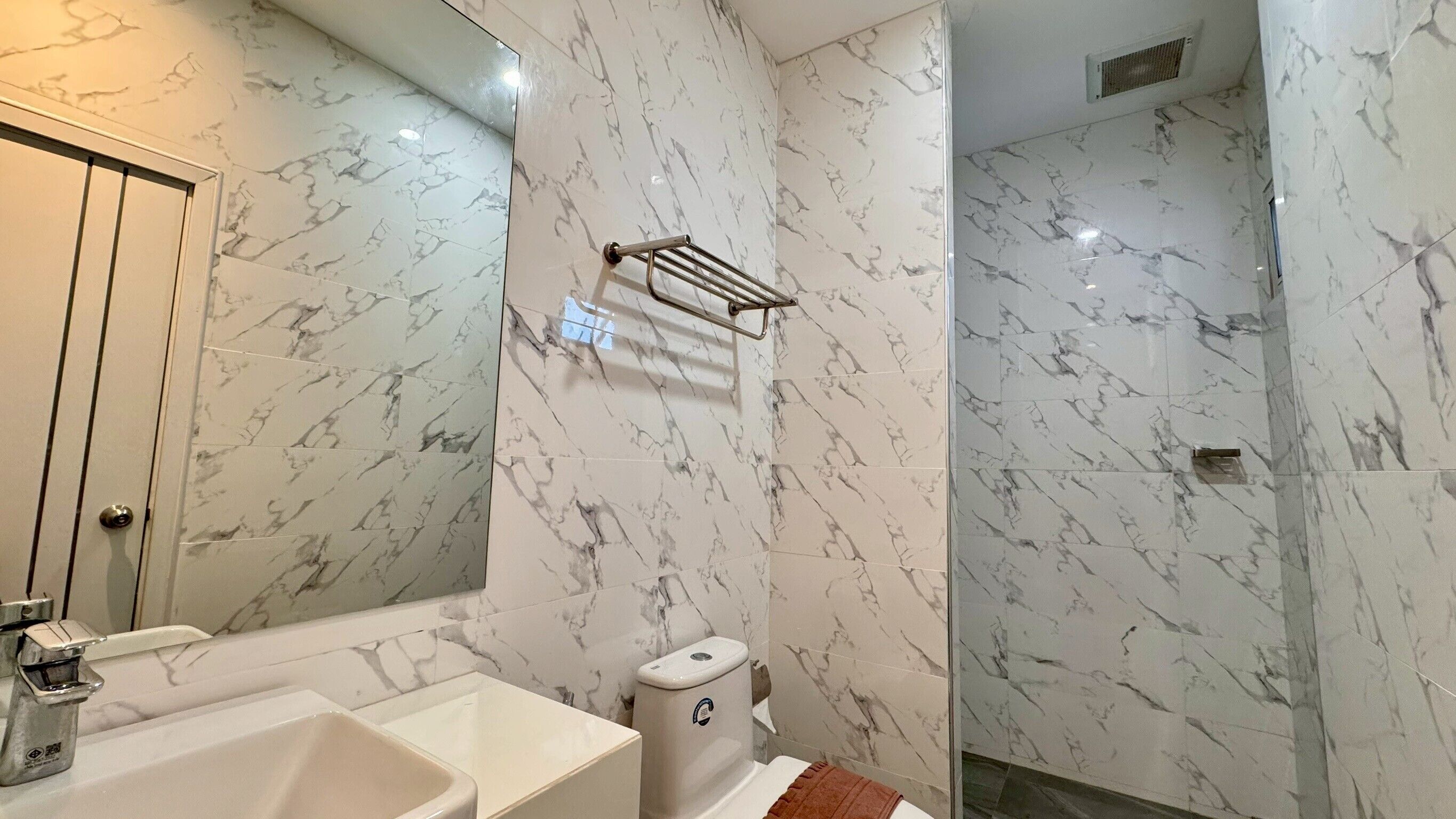 Ein Badezimmer mit Marmorwänden, einer Badewanne, einer Toilette und einer Duschkabine.