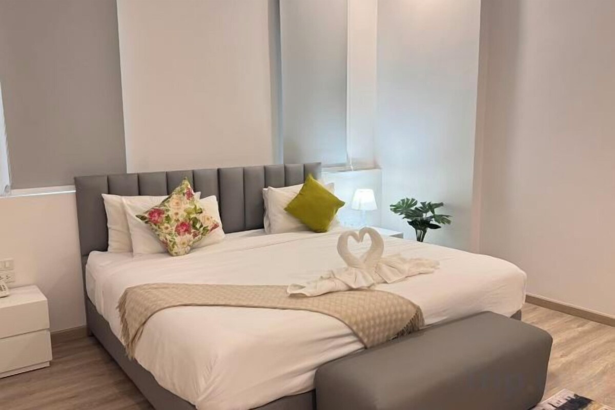 Una habitación de hotel moderna con una cama grande, una mesita de noche y un pequeño escritorio.