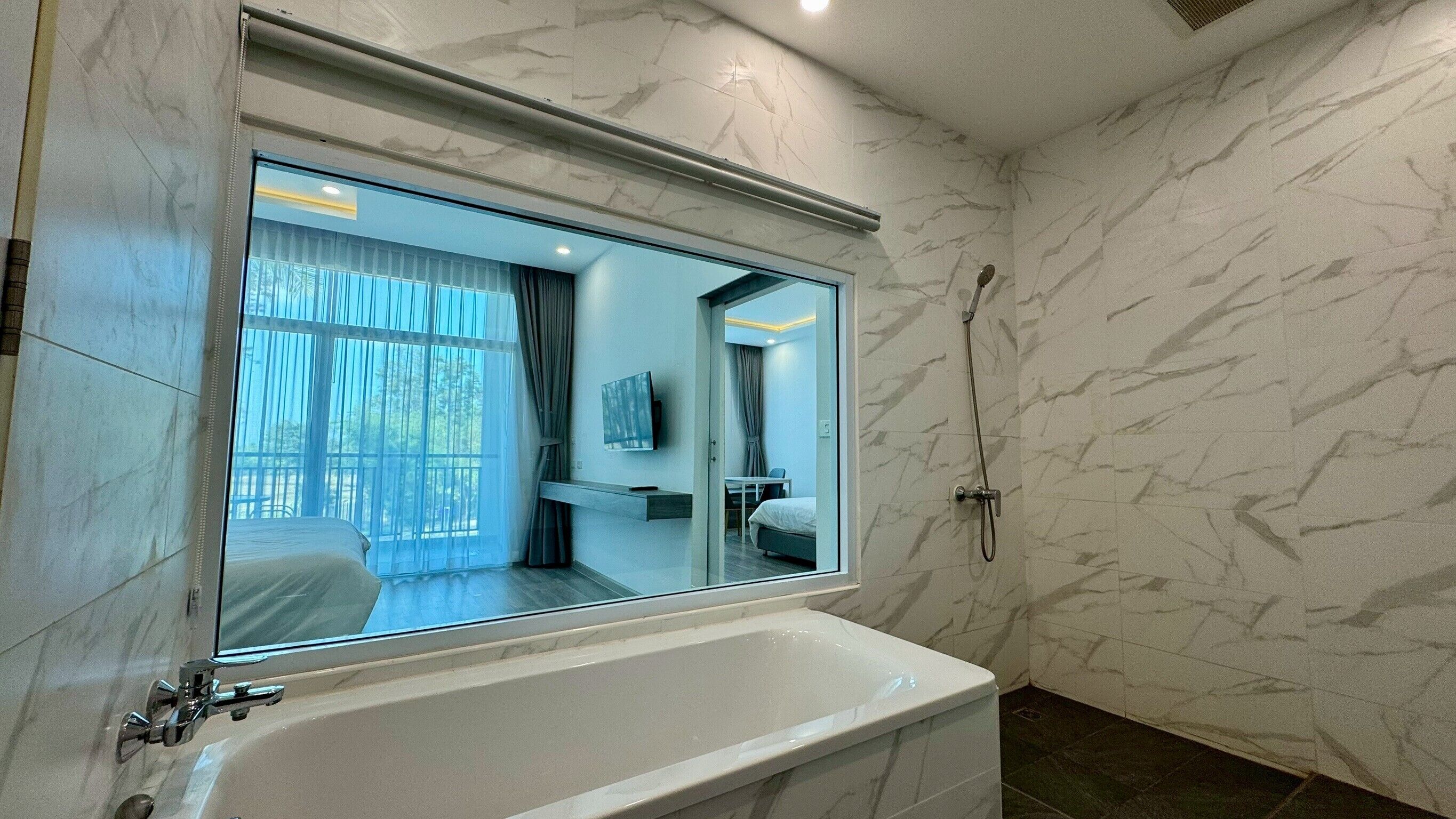 Un baño moderno con un espejo grande, una bañera y una ducha.