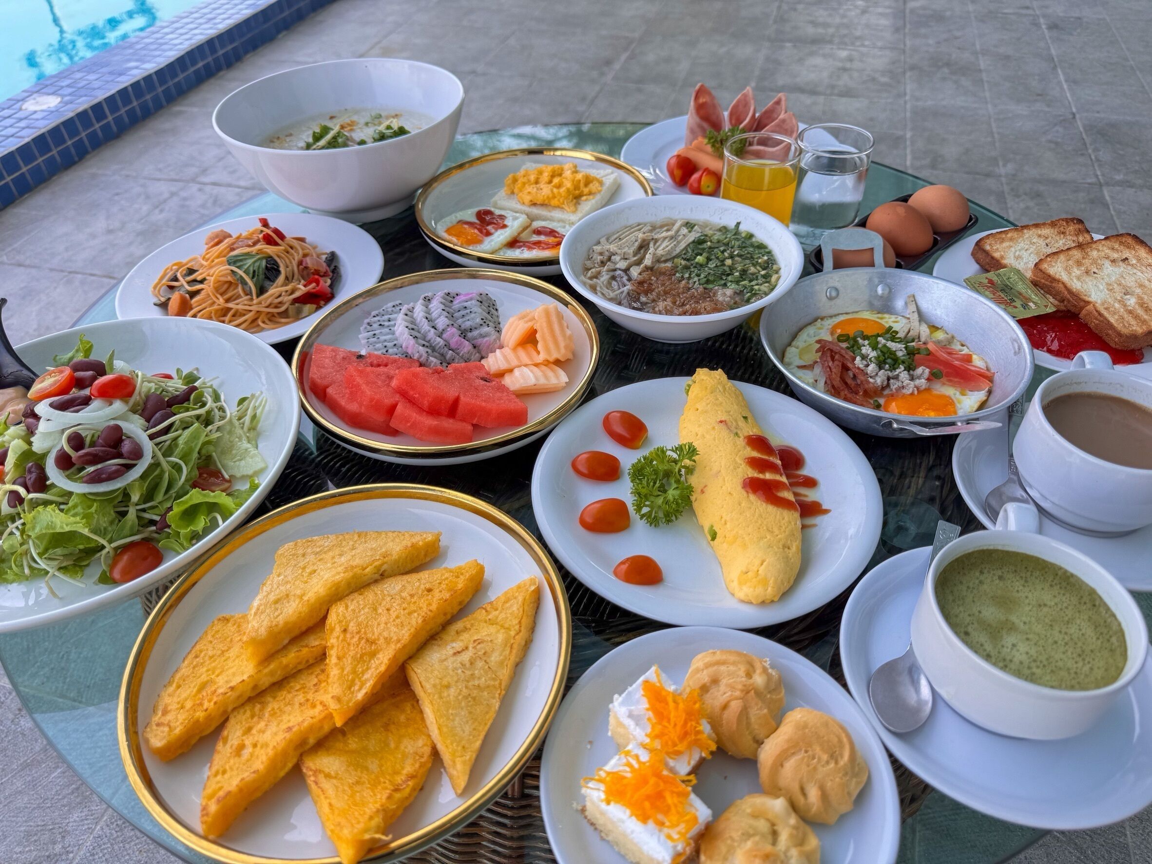 Variedad de platos que incluyen fideos, ensalada, fruta y pan sobre una mesa.