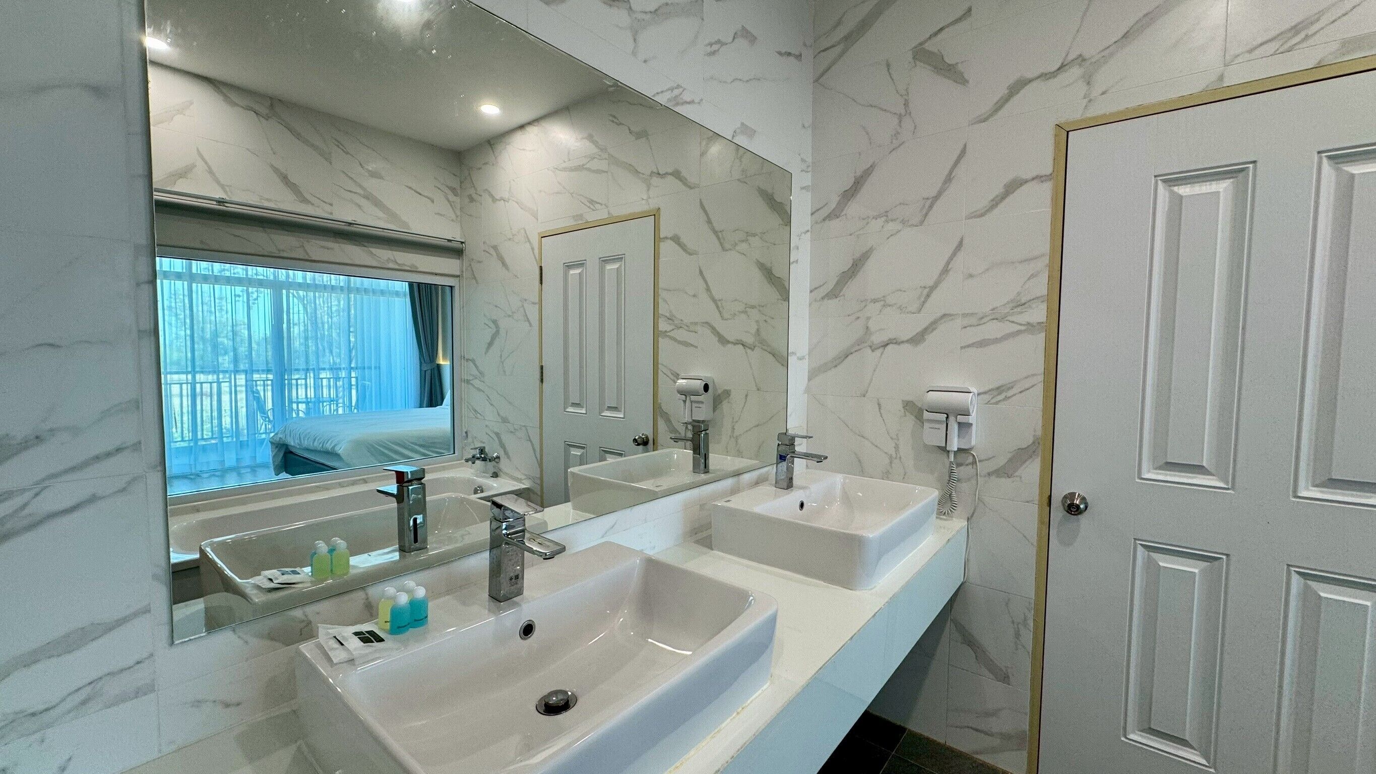 Un baño moderno con tres lavamanos, un espejo grande y vistas a un balcón.