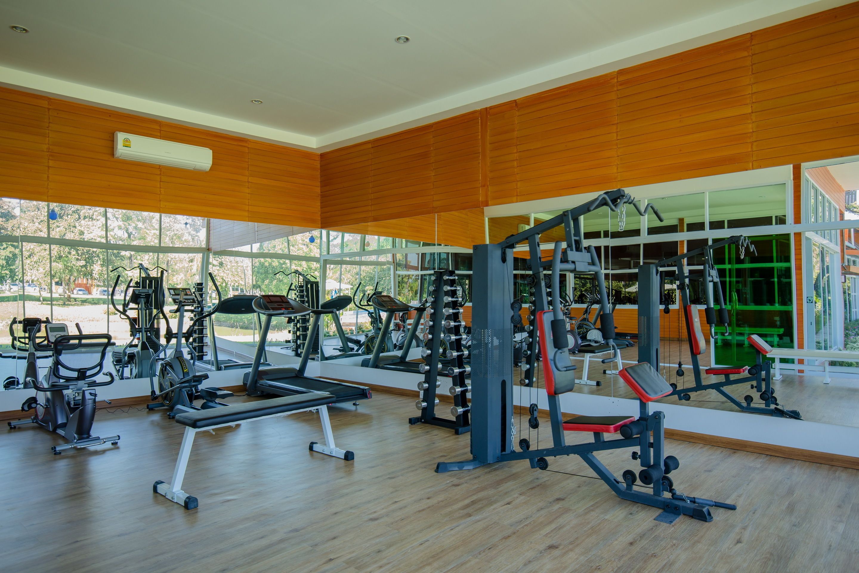 A gym with various exercise equipment, large windows, and a wooden interior.