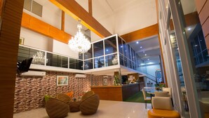 A modern lobby with a high ceiling, a chandelier, a reception desk, and seating areas. - Baan Suan Khunta Golf Resort (Warin Chamrap)
