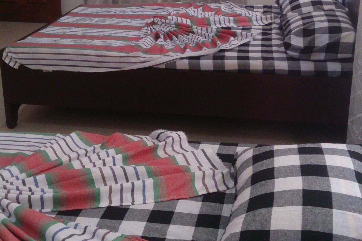 A bedroom with a bed, a checkered pillow, and a striped blanket.