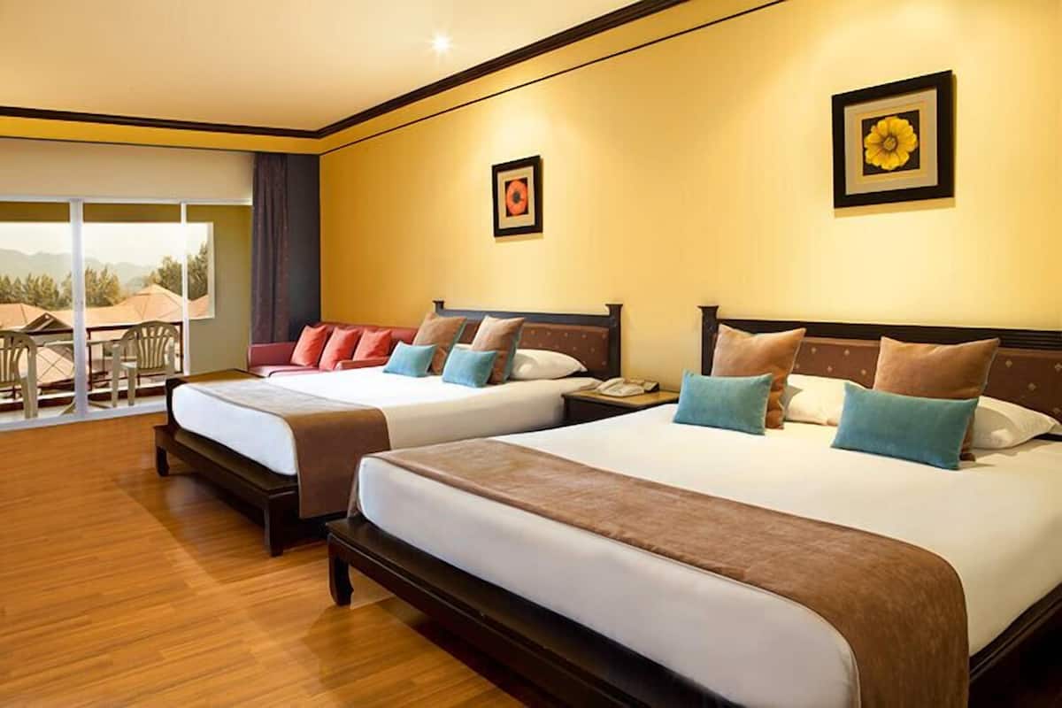 Habitación de hotel con dos camas, un balcón con mobiliario exterior y vistas a las montañas.