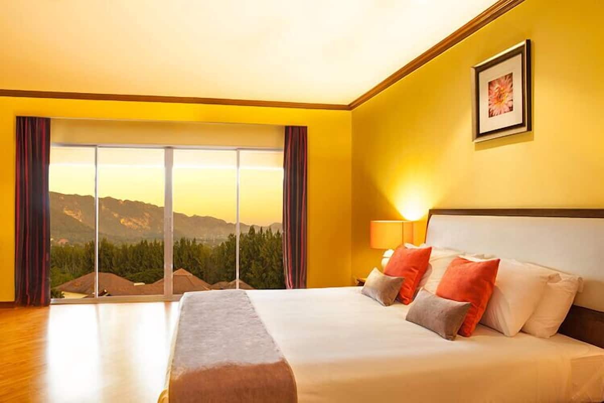 Habitación de hotel con una cama grande, vistas a las montañas y una ventana con cortinas.