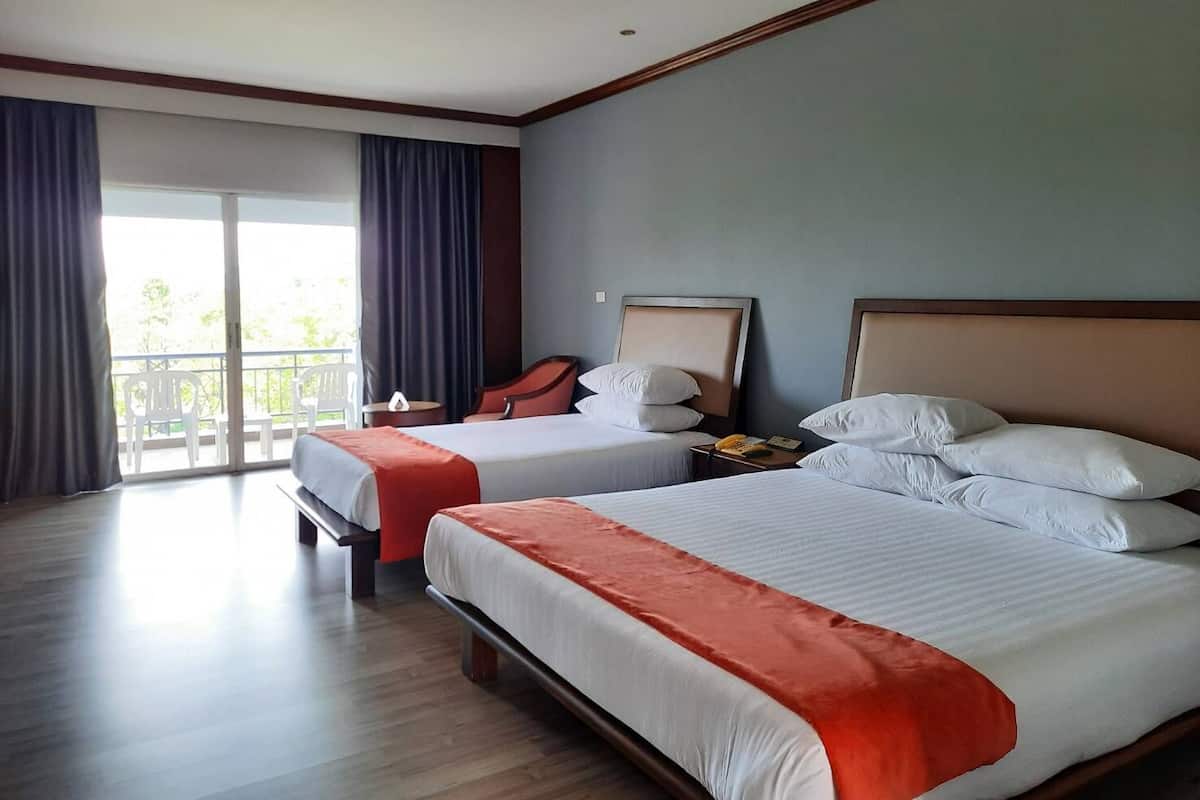 Habitación de hotel con dos camas, balcón y vistas a zonas verdes.