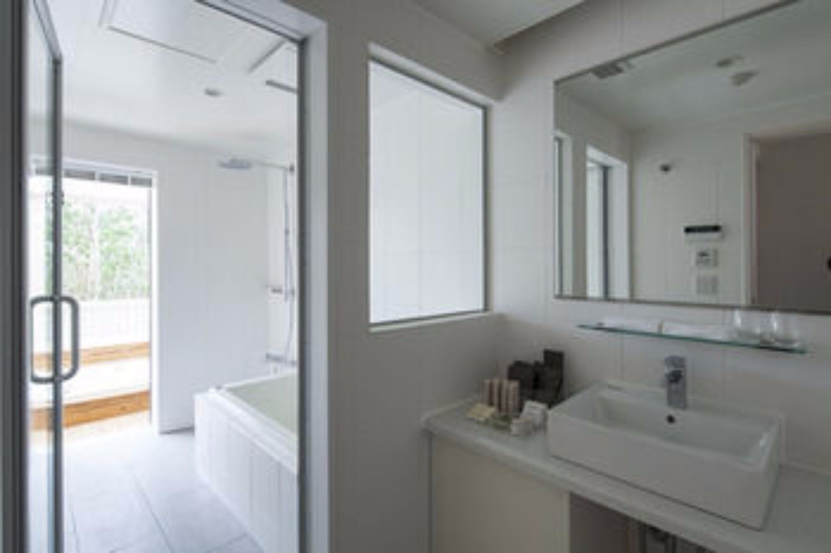 Un bany modern amb un mirall gran, un lavabo blanc i una prestatgeria de vidre.