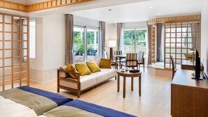 A modern hotel room with a sofa, chairs, a small table, and a desk. Large windows provide natural light and views of the outdoors. - Koyaru-no-sato Doggys Island (Yachimata)