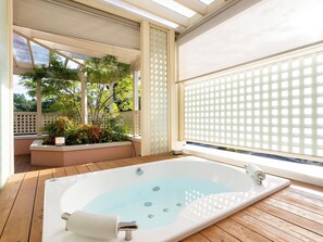 A spa area with a hot tub, wooden deck, and a view of greenery through a window. - Koyaru-no-sato Doggys Island (Yachimata)