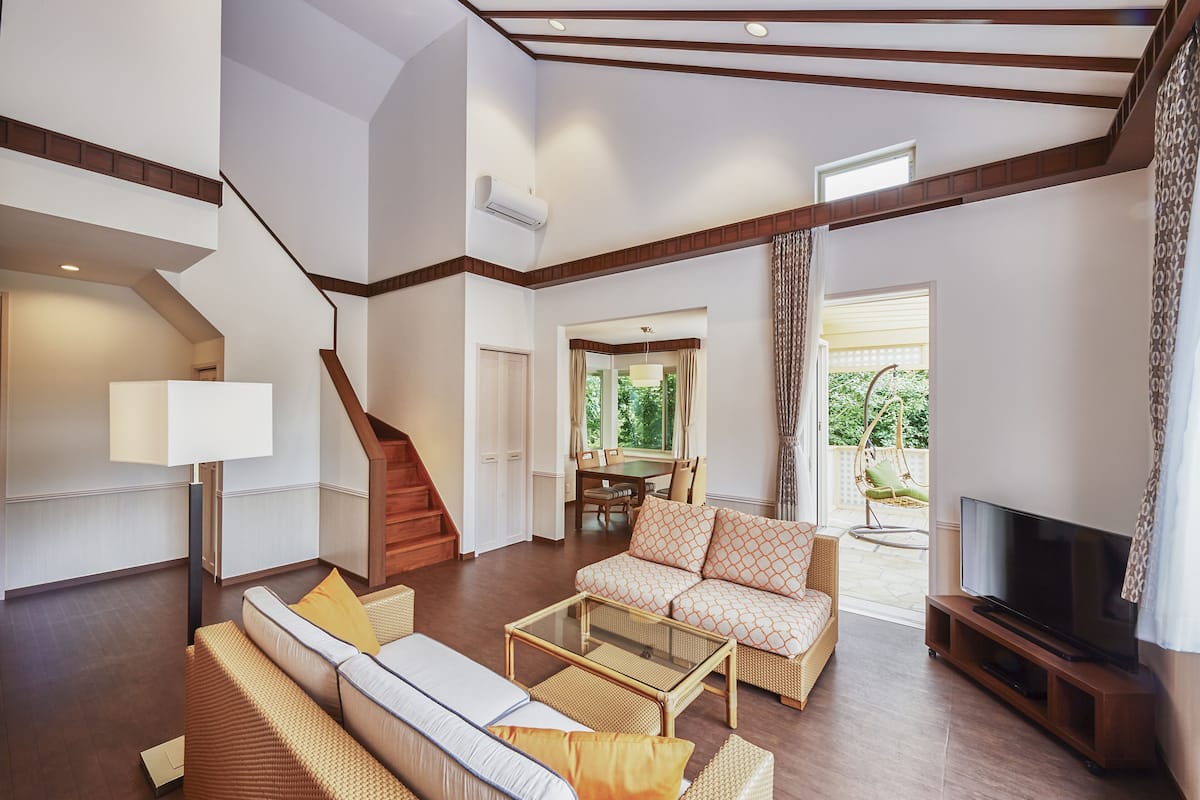 A spacious living room with a sofa, coffee table, and TV. A staircase leads to an upper level.