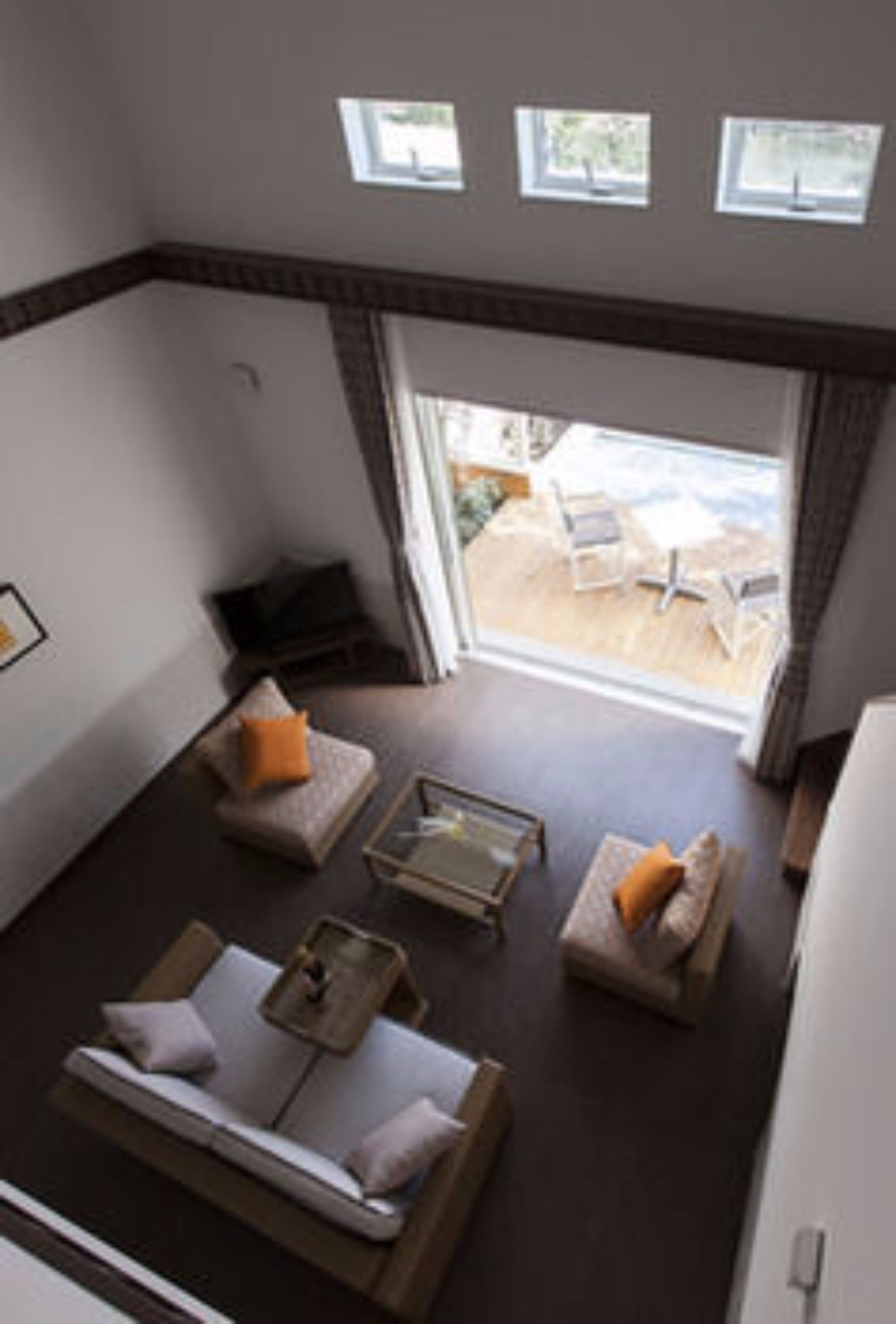 A room with a sofa, a small table, and a window overlooking a deck.