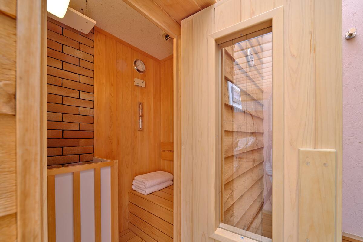A wooden sauna room with a brick wall, a wooden bench, a towel, and a window.