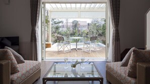 A living room with a glass coffee table, two sofas, and a view of an outdoor patio with a table and chairs. - Koyaru-no-sato Doggys Island (Yachimata)