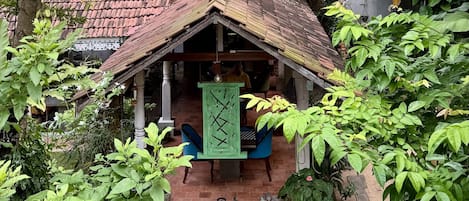 A traditional house with a tiled roof, a porch with a green door, and a brick pathway leading to the entrance.