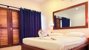 A neatly made bed with white linens, a wooden headboard, and a large mirror above it. - Gomez Place (Negombo)