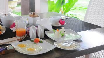 Un desayuno con huevos, jugo y un pájaro decorativo sobre una mesa.