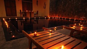 A dining area with tables and chairs, candles, and a stone wall. - Gomez Place (Negombo)