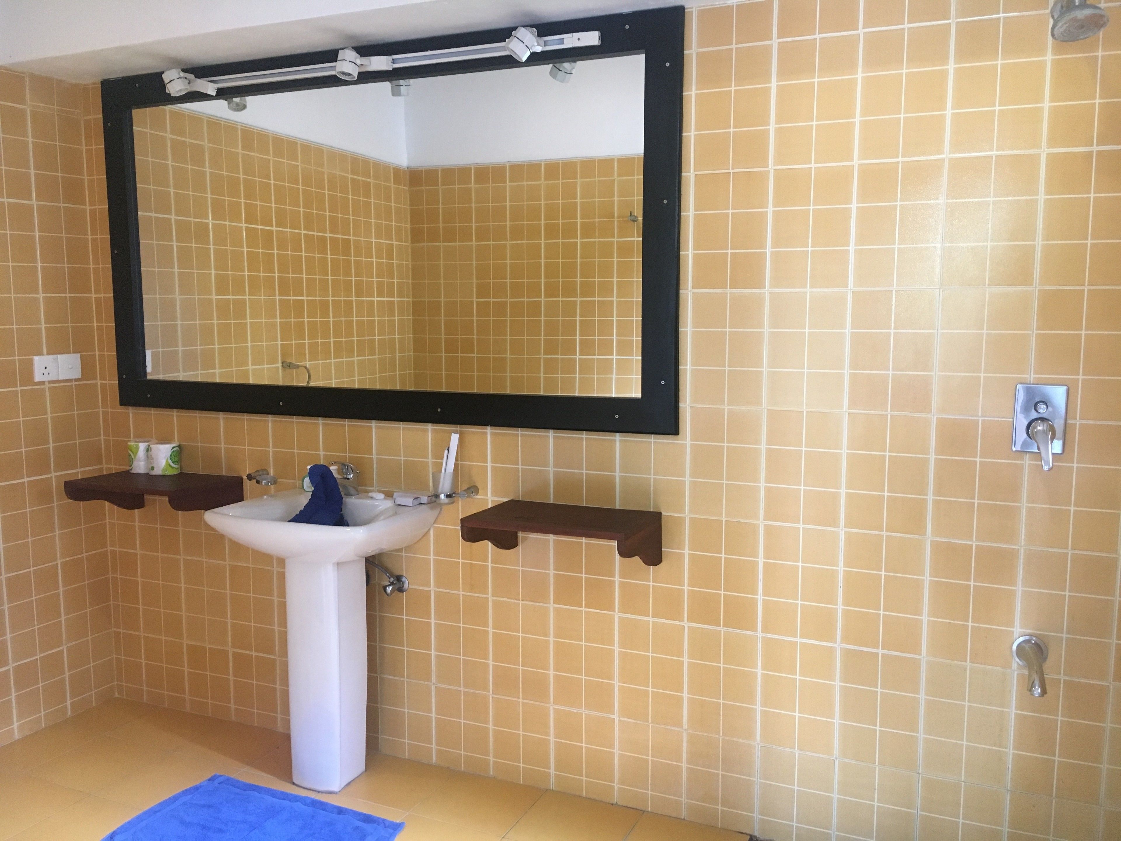 A bathroom with a white sink, mirror, and tiled walls.