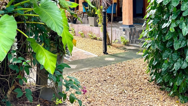 A courtyard with a wooden pergola, potted plants, and a pathway. - Gomez Place (Negombo)
