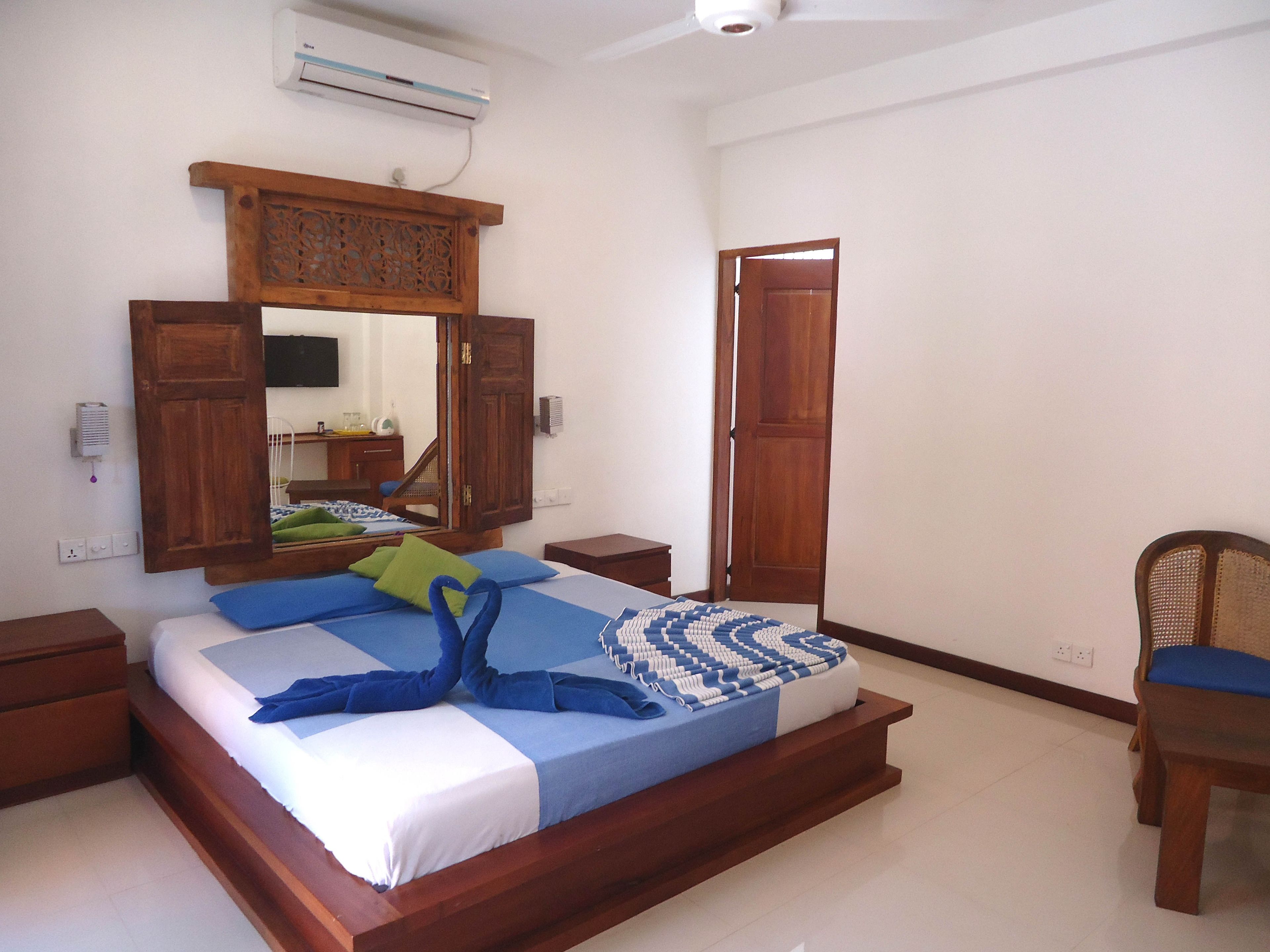 Un dormitorio con una cama de madera, una mesita de noche, una silla, un armario y un espejo.