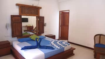 Un dormitorio con una cama de madera, una mesita de noche, una silla, un armario y un espejo.