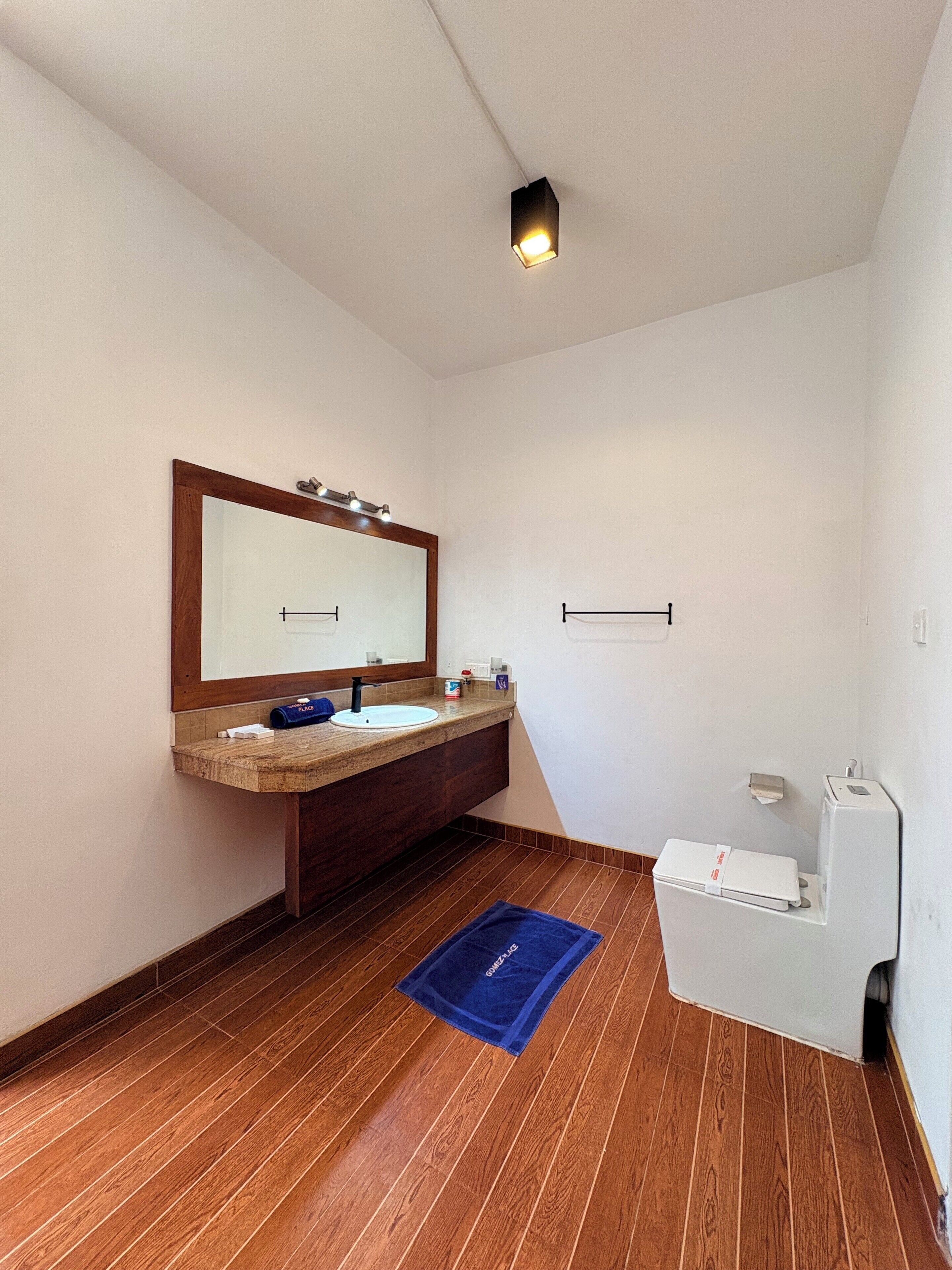 A bathroom with a wooden vanity, a mirror, a towel, and a toilet.